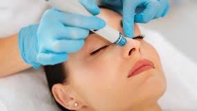 HydraFacial handpiece gliding across woman's cheek